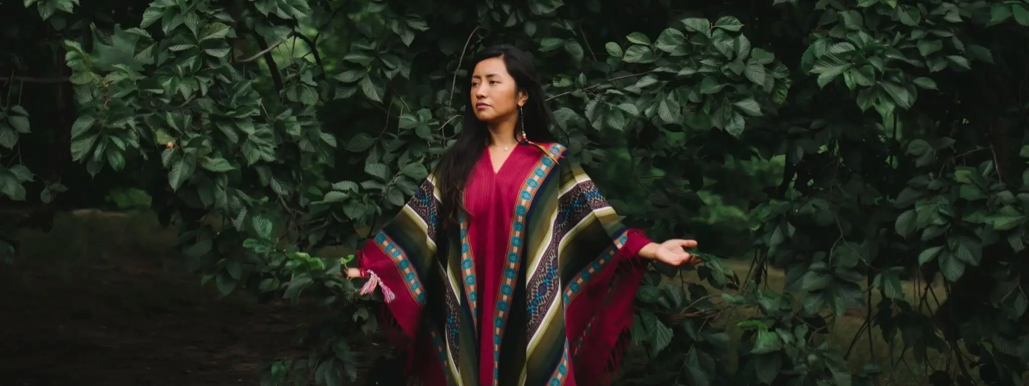 Rossana in a woven Andean poncho surrounded by the green mountains of the Sacred Valley